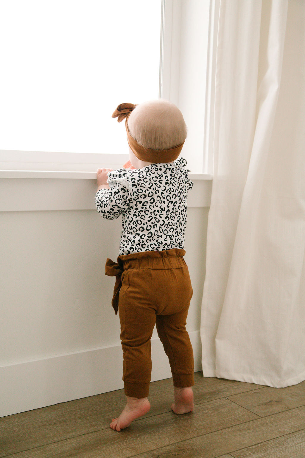 3 piece baby girl leopard printed bodysuit with ruffle shoulders & snaps. Rust pants with matching headband.