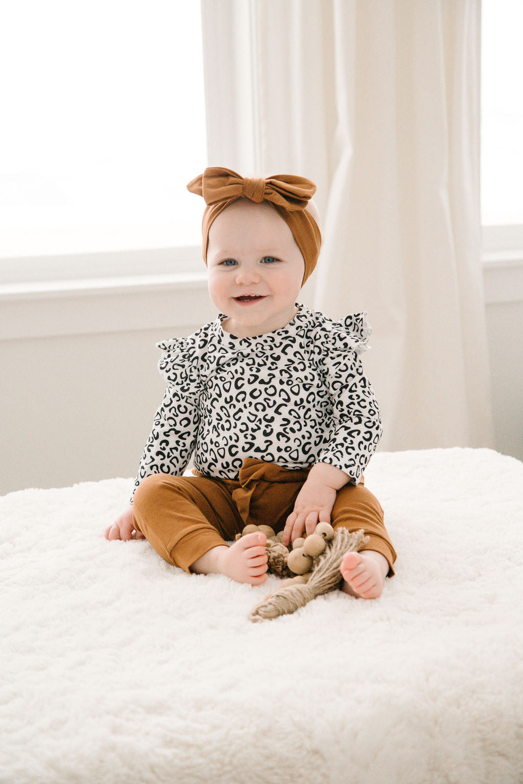 3 piece baby girl leopard printed bodysuit with ruffle shoulders & snaps. Rust pants with matching headband.