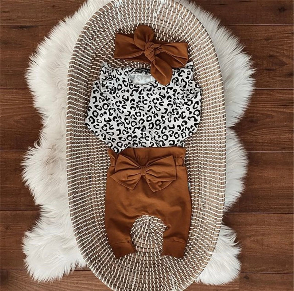 3 piece baby girl leopard printed bodysuit with ruffle shoulders & snaps. Rust pants with matching headband.