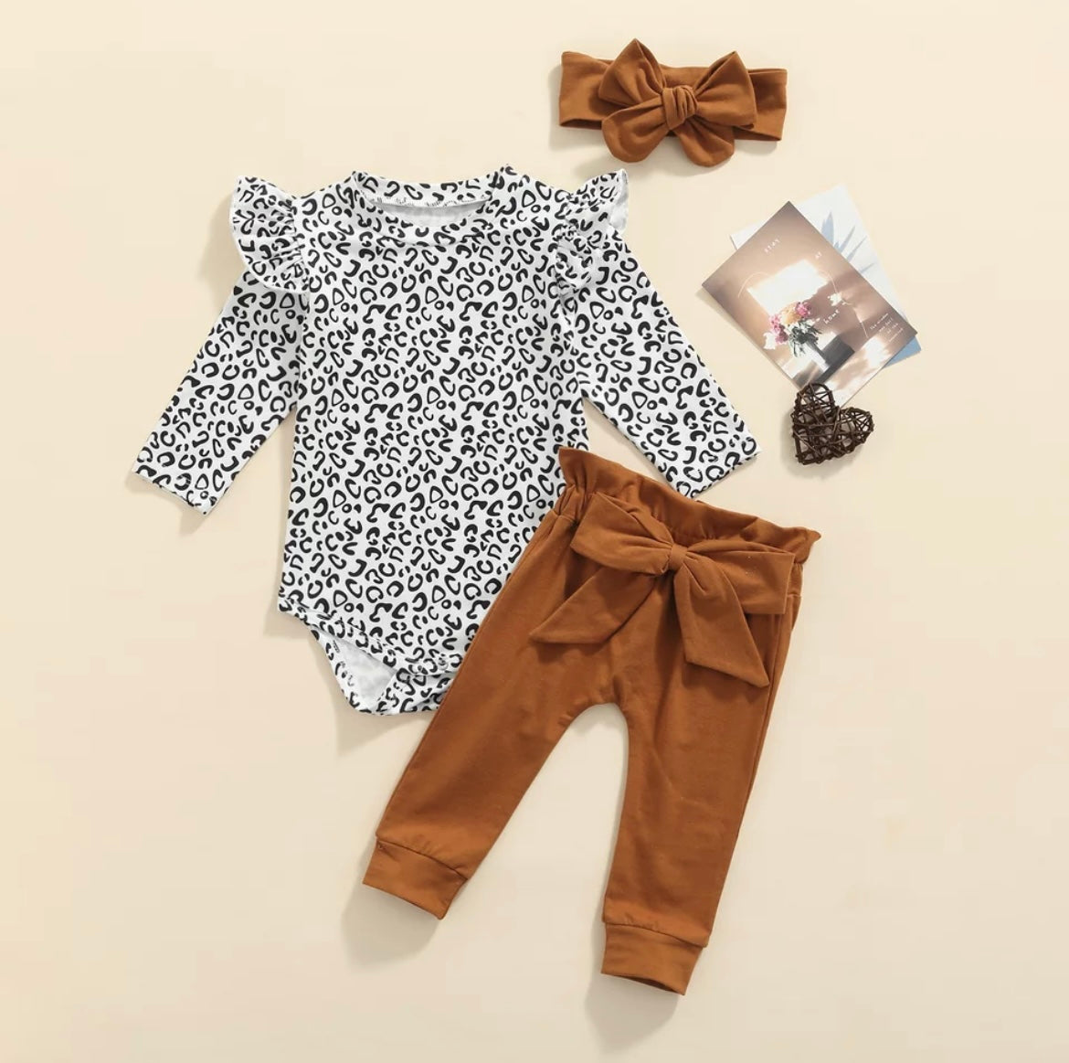 3 piece baby girl leopard printed bodysuit with ruffle shoulders & snaps. Rust pants with matching headband.