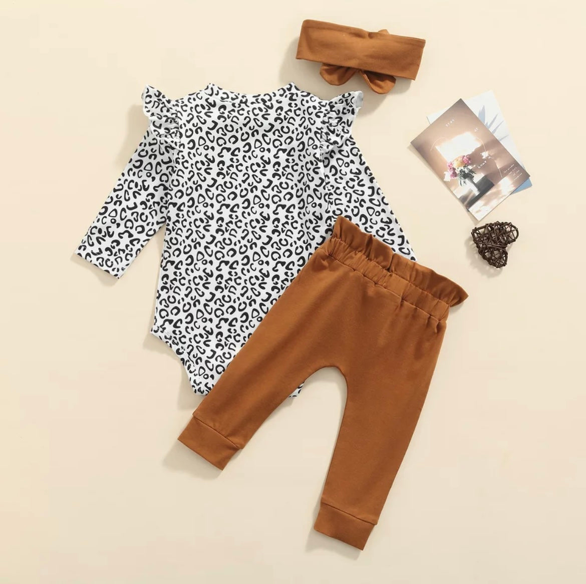 3 piece baby girl leopard printed bodysuit with ruffle shoulders & snaps. Rust pants with matching headband.