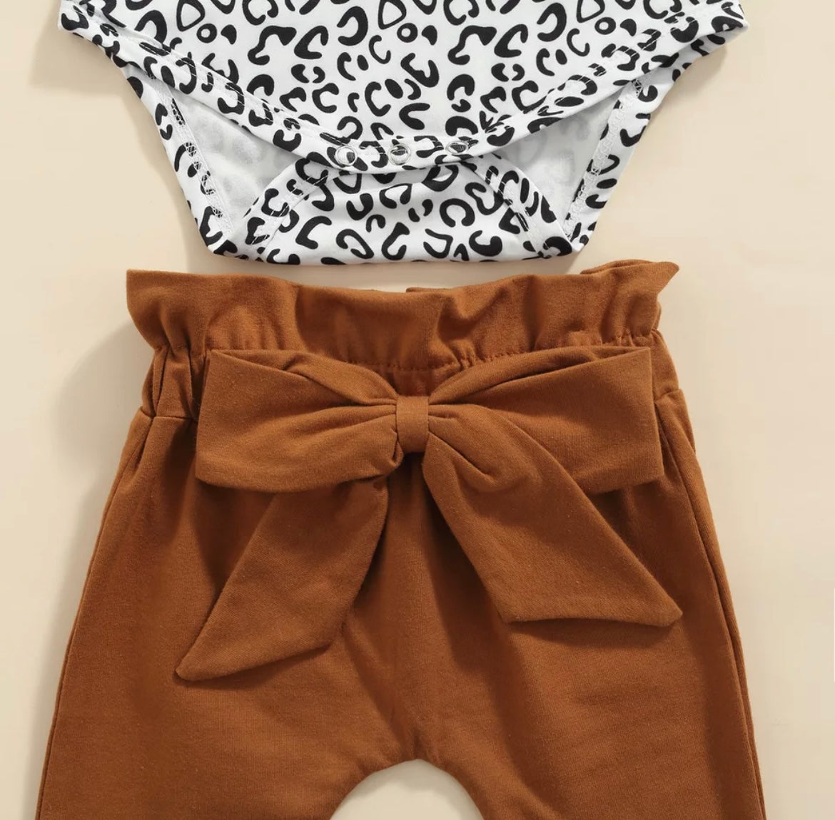 3 piece baby girl leopard printed bodysuit with ruffle shoulders & snaps. Rust pants with matching headband.