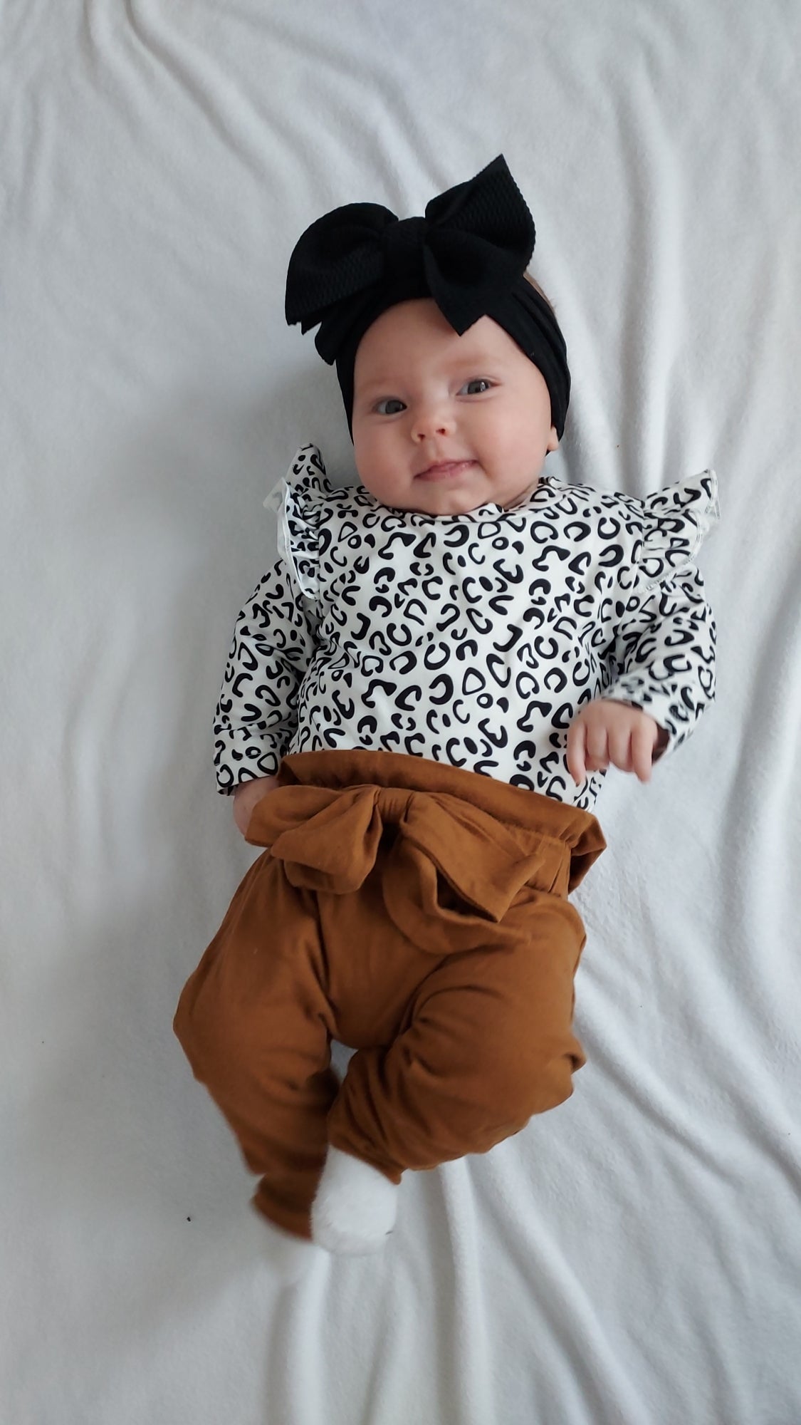 3 piece baby girl leopard printed bodysuit with ruffle shoulders & snaps. Rust pants with matching headband.